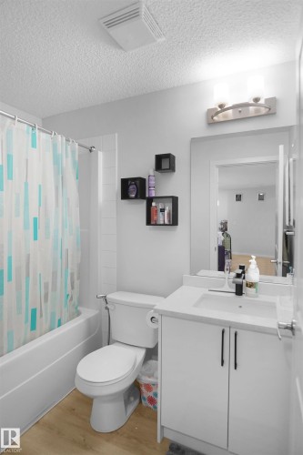 Bathroom featuring a white vanity with a rectangular sink, light-toned flooring, and a shower-tub combination - 103 3353 16A Avenue, Edmonton, AB - Indoor Photo Showing Bathroom