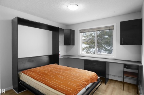 This room features a built-in wall bed, integrated desk space with drawers, and wall-mounted cabinetry - 103 3353 16A Avenue, Edmonton, AB - Indoor Photo Showing Bedroom