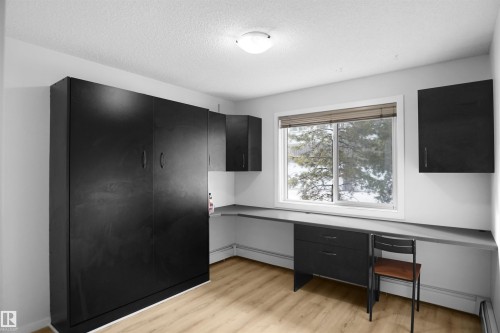 This room features a built-in wall unit, a wide window with a view of trees and snow, and light-toned flooring - 103 3353 16A Avenue, Edmonton, AB - Indoor