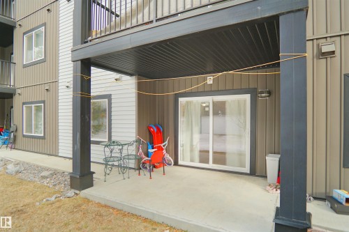 The property features a concrete patio area with direct access to the interior through a sliding glass door - 103 3353 16A Avenue, Edmonton, AB - Outdoor With Exterior