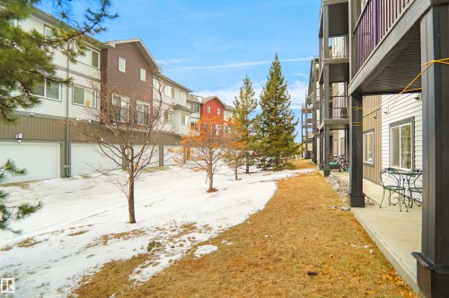 The property features a row of garages, several outdoor balconies, and a patio area with outdoor seating - 103 3353 16A Avenue, Edmonton, AB - Outdoor