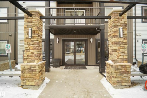 The property entrance features stone-clad pillars, a covered entryway, and a glass-paneled door - 103 3353 16A Avenue, Edmonton, AB - Outdoor