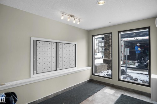The property features a mailbox wall unit, track lighting, and recessed lighting - 103 3353 16A Avenue, Edmonton, AB - Indoor Photo Showing Other Room
