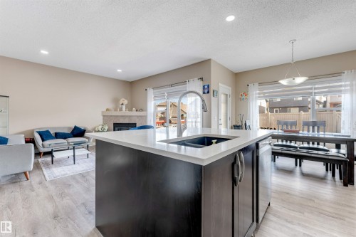 Open concept living area featuring a kitchen island with a sink, light-toned flooring, and recessed lighting - 121 64 Street, Edmonton, AB - Indoor Photo Showing Kitchen With Double Sink With Upgraded Kitchen