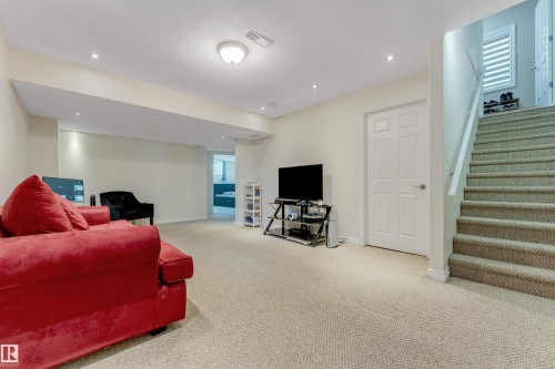 Spacious finished area featuring light-colored carpeting, recessed lighting, and a painted paneled door - 121 64 Street, Edmonton, AB - Indoor