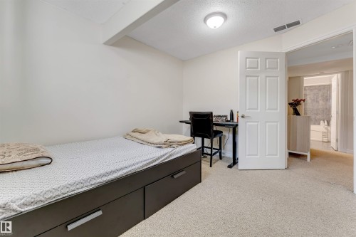 This room features light-colored walls and carpeting, a ceiling light fixture, and a white paneled door - 121 64 Street, Edmonton, AB - Indoor Photo Showing Bedroom