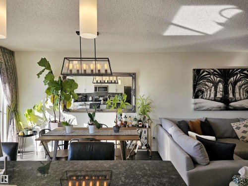 Dining area and living room featuring a large light fixture, a spacious dining table, and a sectional sofa - 6888 Evans Wynd, Edmonton, AB - Indoor