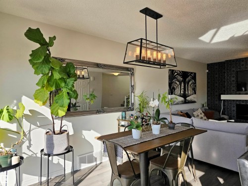 The property features an open living and dining area with light-colored walls and dark flooring - 6888 Evans Wynd, Edmonton, AB - Indoor Photo Showing Dining Room