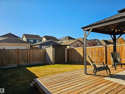 The property features a spacious backyard with a wooden deck, a well-maintained lawn, and a storage shed - 6888 Evans Wynd, Edmonton, AB - Outdoor With Deck Patio Veranda