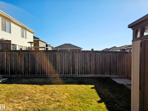 The property features a fenced yard with a lawn and a paved area - 6888 Evans Wynd, Edmonton, AB - Outdoor