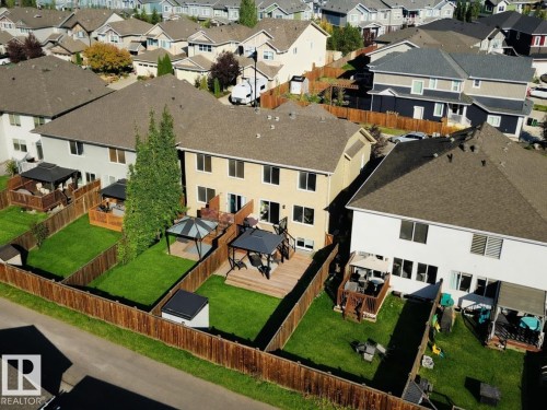 The property features a spacious backyard with a well-maintained lawn, a wooden deck, and a gazebo - 6888 Evans Wynd, Edmonton, AB - Outdoor With Deck Patio Veranda