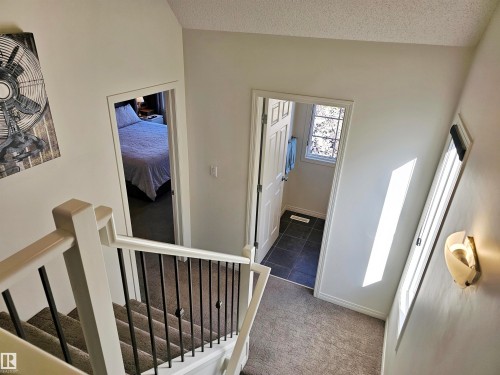 This property features a staircase with a white banister and black spindles, leading to carpeted areas - 6888 Evans Wynd, Edmonton, AB - Indoor
