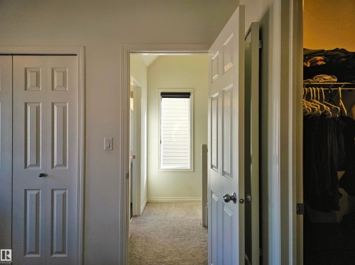 Interior hallway with light-colored carpeting, white walls, and a window with blinds - 6888 Evans Wynd, Edmonton, AB - Indoor Photo Showing Other Room