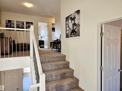 Well-maintained staircase with light-colored carpet, white risers, and a white and silver railing - 6888 Evans Wynd, Edmonton, AB - Indoor Photo Showing Other Room