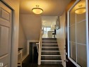 Inviting entryway featuring tile flooring, a staircase with white risers, and a door with a window providing natural light - 6888 Evans Wynd, Edmonton, AB  - Indoor Photo Showing Other Room 