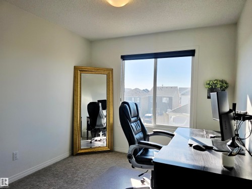 This room features a window with a view of the surrounding neighborhood, light-colored walls, and textured carpeting - 6888 Evans Wynd, Edmonton, AB - Indoor Photo Showing Office