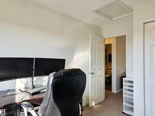 This room features light-colored walls and carpeted flooring, with a visible white door and an access panel in the ceiling - 6888 Evans Wynd, Edmonton, AB - Indoor Photo Showing Office