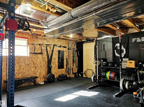 Well-appointed fitness space featuring exposed wood beam ceilings, rubber flooring, and a window for natural light - 6888 Evans Wynd, Edmonton, AB - Indoor Photo Showing Basement