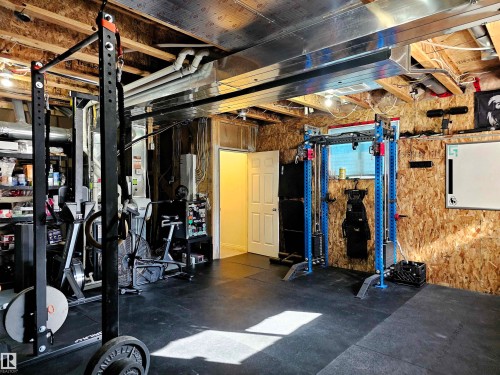 The property features an unfinished basement with exposed wood joists and ductwork, providing a flexible space with durable black rubber flooring - 6888 Evans Wynd, Edmonton, AB - Indoor Photo Showing Basement