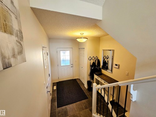 This property features an entryway with tiled flooring and a white front door with upper window panes - 6888 Evans Wynd, Edmonton, AB - Indoor Photo Showing Other Room