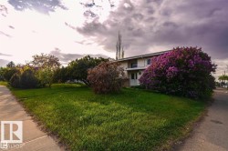 The property features a well-maintained lawn with mature trees and a prominent flowering shrub - 