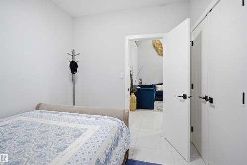 This room features white walls, a bed with a patterned bedspread, and two white doors with black hardware - 2420 13 Avenue, Edmonton, AB - Indoor Photo Showing Bedroom