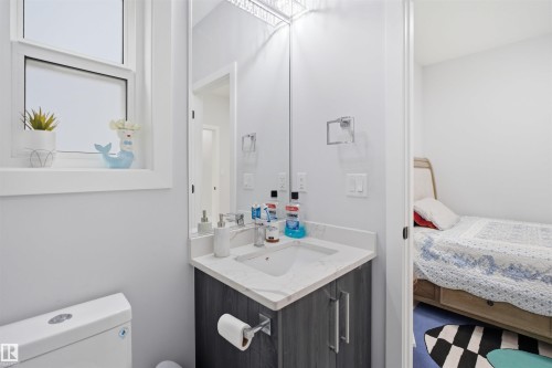Bathroom featuring a window, toilet, vanity with a light-colored countertop, and a mirror - 2420 13 Avenue, Edmonton, AB - Indoor Photo Showing Bathroom