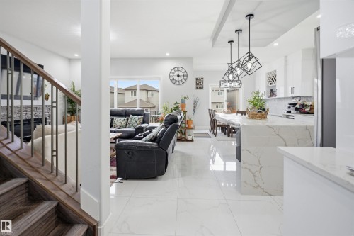 Light-filled open concept living space featuring a modern kitchen with a large island and pendant lighting, a dining area, and a living room with a large window - 2420 13 Avenue, Edmonton, AB - Indoor Photo Showing Other Room