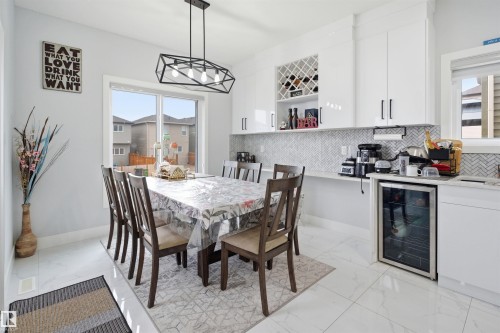 This dining area features white tile flooring and a modern geometric light fixture - 2420 13 Avenue, Edmonton, AB - Indoor Photo Showing Dining Room