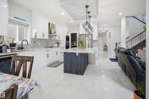 Modern kitchen featuring white cabinetry, a large island with a light-colored countertop, and stainless steel appliances - 2420 13 Avenue, Edmonton, AB - Indoor Photo Showing Kitchen With Upgraded Kitchen