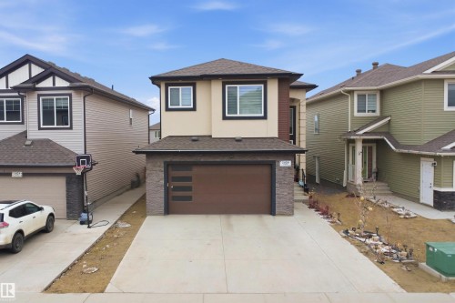 This property features a modern exterior with a mix of beige stucco and dark stone accents, complemented by a brown garage door with horizontal frosted glass inserts - 2420 13 Avenue, Edmonton, AB - Outdoor