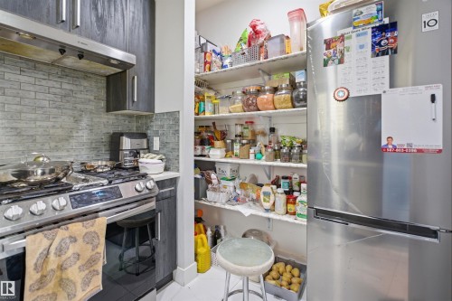 The kitchen features dark wood cabinetry, a stainless steel range with an overhead exhaust, and a tiled backsplash - 2420 13 Avenue, Edmonton, AB - Indoor Photo Showing Kitchen