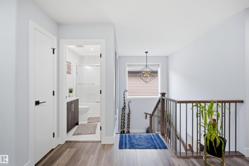 Well-lit hallway featuring light hardwood floors and a modern staircase with dark wood railings - 2420 13 Avenue, Edmonton, AB - Indoor Photo Showing Other Room