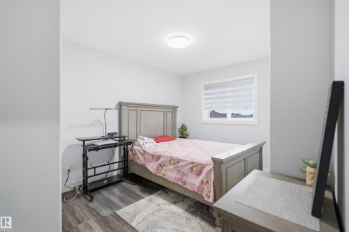 This room features light grey walls, dark wood-style flooring, and a single window with blinds - 2420 13 Avenue, Edmonton, AB - Indoor Photo Showing Bedroom