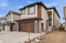 The property features a two-story design with a light-colored stucco exterior, dark trim, and a dark brown garage door with frosted glass panels - 2420 13 Avenue, Edmonton, AB  - Outdoor 