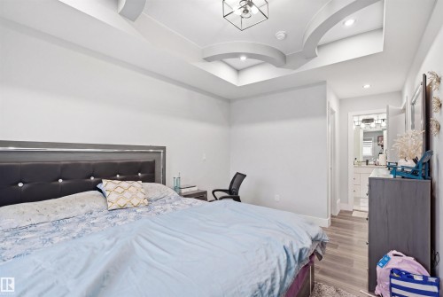 This bedroom features light-colored walls and flooring, with a tray ceiling providing architectural detail - 2420 13 Avenue, Edmonton, AB - Indoor Photo Showing Bedroom