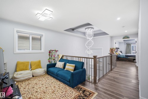 This property features a spacious landing area with hardwood flooring, a modern chandelier, and a decorative ceiling detail - 2420 13 Avenue, Edmonton, AB - Indoor