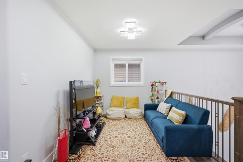 This versatile bonus room offers a window, a modern ceiling light fixture, and a decorative railing - 2420 13 Avenue, Edmonton, AB - Indoor