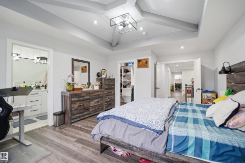 This property features a bedroom with stylish wood-look flooring and a distinctive tray ceiling with exposed beams - 2420 13 Avenue, Edmonton, AB - Indoor Photo Showing Bedroom