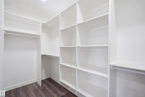 The property features a closet with white built-in shelving, white hanging rods, and dark wood flooring - 2420 13 Avenue, Edmonton, AB - Indoor With Storage