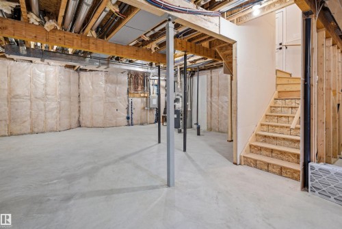 The property features an unfinished basement with a concrete floor, exposed wooden beams, and a wooden staircase - 2420 13 Avenue, Edmonton, AB - Indoor Photo Showing Basement