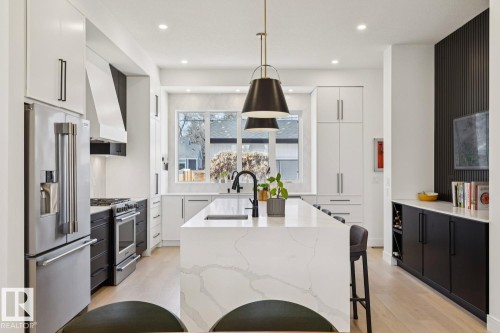 The kitchen features a large island with a waterfall countertop, stainless steel appliances, and ample white cabinetry - 11146 62 Street Nw, Edmonton, AB - Indoor Photo Showing Kitchen With Upgraded Kitchen