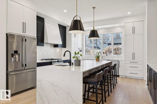 The kitchen features a large center island with a white countertop, equipped with a sink and a black faucet - 11146 62 Street Nw, Edmonton, AB - Indoor Photo Showing Kitchen With Upgraded Kitchen