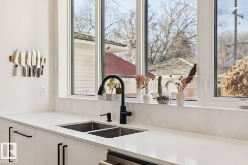 The kitchen features a double basin stainless steel sink with a matte black faucet, set into white countertops - 11146 62 Street Nw, Edmonton, AB - Indoor Photo Showing Kitchen With Double Sink