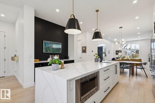 The kitchen features a large island with a microwave, a white countertop, and pendant lighting - 11146 62 Street Nw, Edmonton, AB - Indoor Photo Showing Kitchen With Upgraded Kitchen