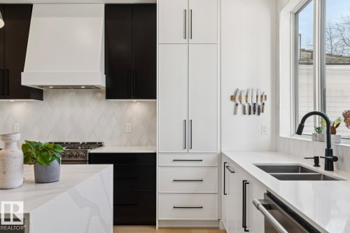 The kitchen features white shaker-style cabinetry, black lower cabinets, white countertops, and a stainless steel oven range - 11146 62 Street Nw, Edmonton, AB - Indoor Photo Showing Kitchen With Double Sink With Upgraded Kitchen