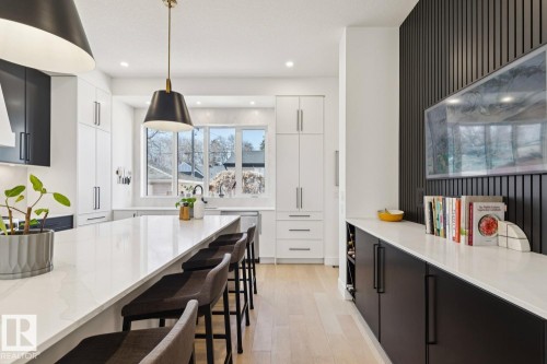 The kitchen features an expansive island with a white countertop and seating, complemented by recessed lighting and pendant fixtures - 11146 62 Street Nw, Edmonton, AB - Indoor