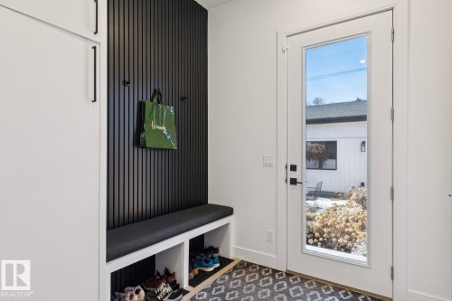 Entryway featuring built-in storage with a cushioned bench, a slat wall with hooks, and patterned floor tiles - 11146 62 Street Nw, Edmonton, AB - Indoor Photo Showing Other Room