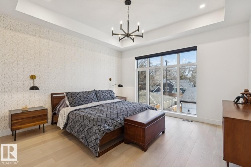 Bedroom featuring light-toned flooring, large windows, and a modern chandelier - 11146 62 Street Nw, Edmonton, AB - Indoor Photo Showing Bedroom