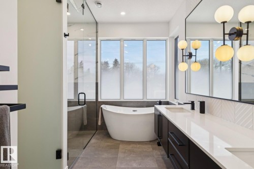 This bathroom features a freestanding soaking tub, a large vanity with dual sinks, and a spacious glass-enclosed shower - 11146 62 Street Nw, Edmonton, AB - Indoor Photo Showing Bathroom